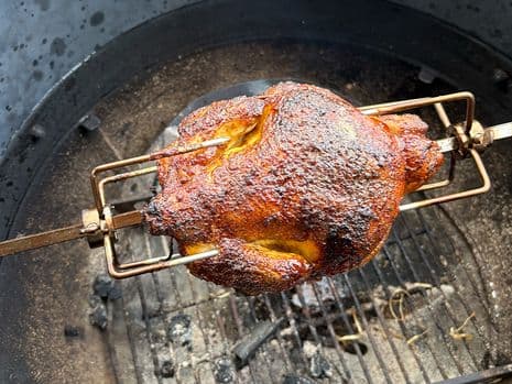 Geroosterde kip aan het spit, goudbruin en knapperig, in een kletelbarbecue.