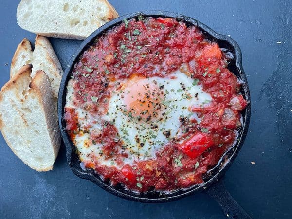 Shakshuka in een skillet met stukjes brood er omheen