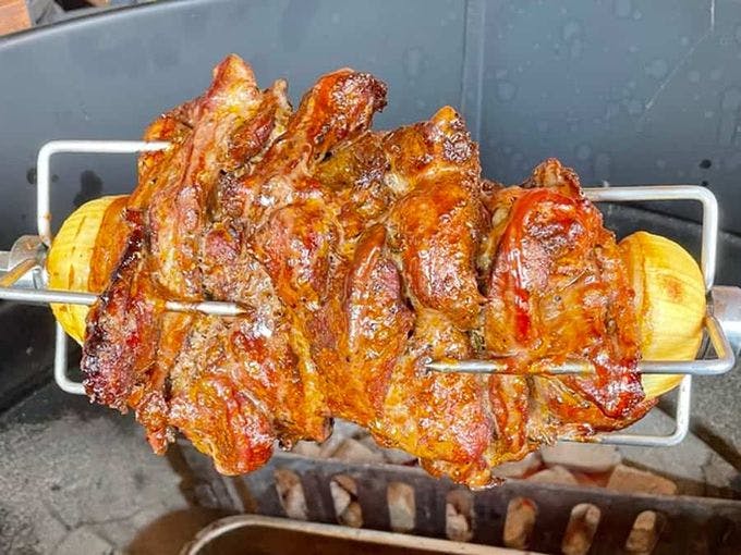 gyros van varkensvlees aan een spit boven hete kolen op een barbecue