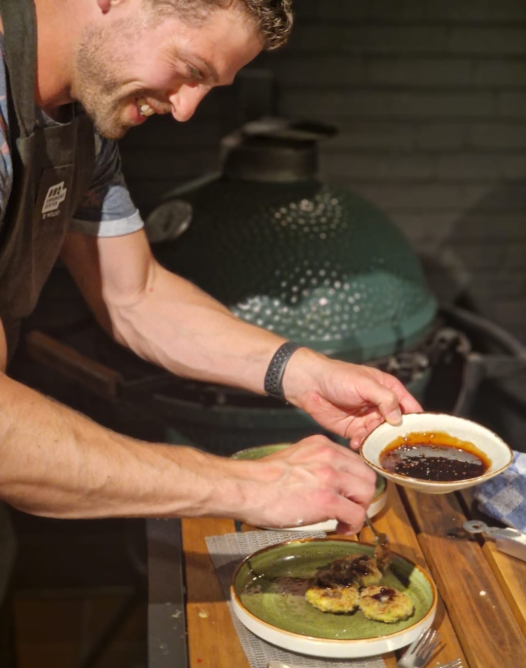 Rogier (Roog BBQ) drapeert een chilisaus over viskoekjes op een bord