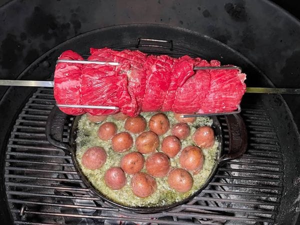 Een rauwe bavette rollade aan het spit in een barbecue.