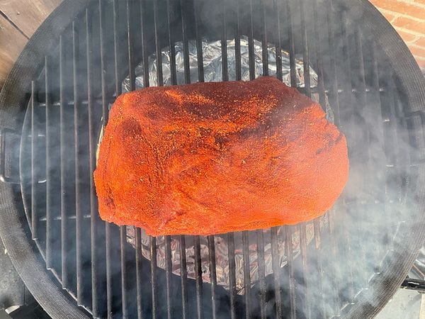 pulled pork op een barbecue rooster met rook er omheen