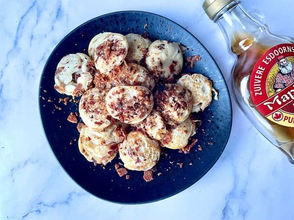 poffertjes met bacon crumble en ahorn siroop op een zwart bord