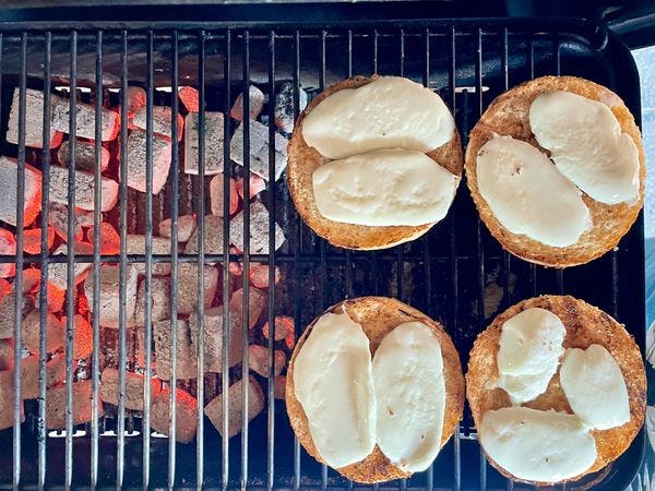 Hamburger broodjes op een indirect deel van een barbecue met mozzarella er op