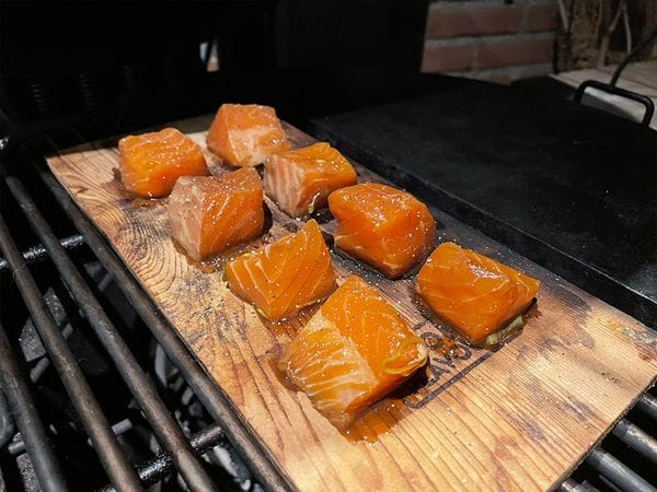 zalm bonbons op een cederhouten plank op een barbecue rooster boven directe hitte