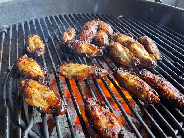 kipvleugels in barbecuesaus op een rooster boven het vuur van een barbecue
