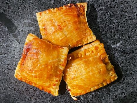3 Pulled pork bladerdeeg hapjes op een zwart bord