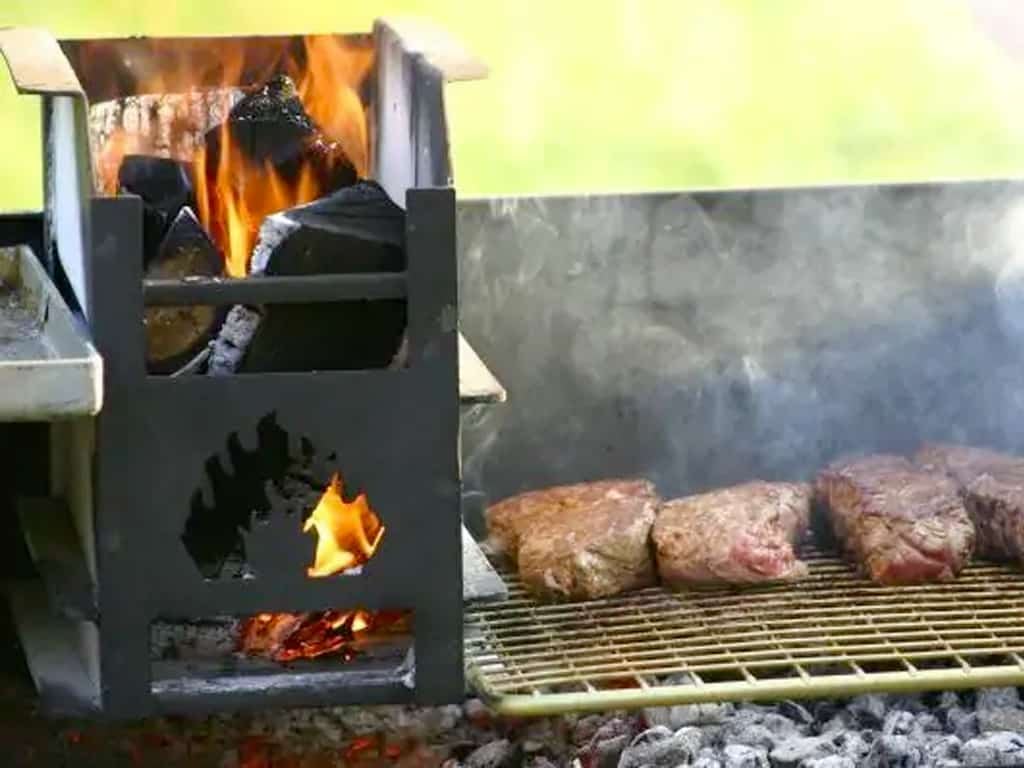 Een Zuid-Afrikaanse braai met vlees op het rooster en brandende blokken hout in de vuurkorf
