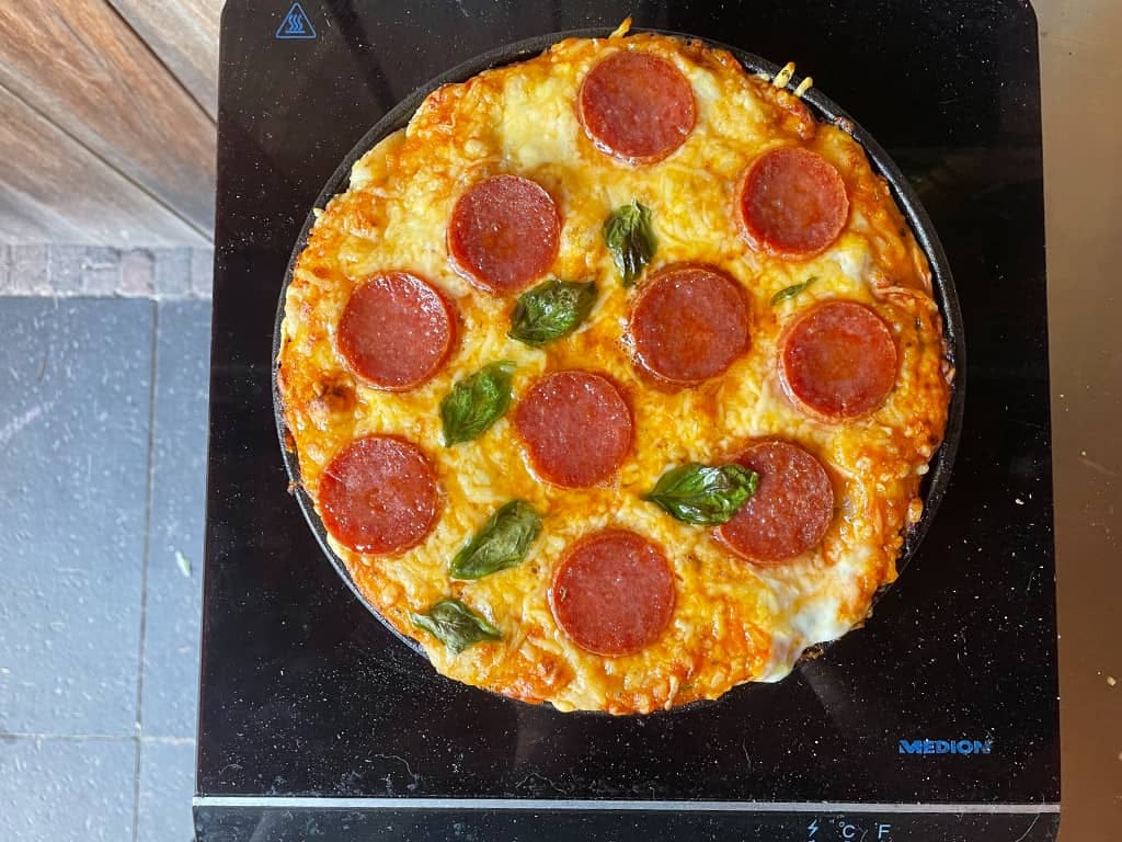 pan pizza in skillet wordt aangebakken op een inductie kookplaat