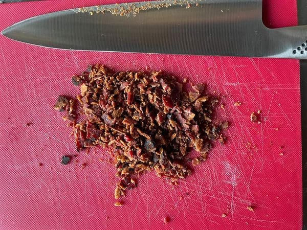 bacon crumble op een snijplank met een mes ernaast