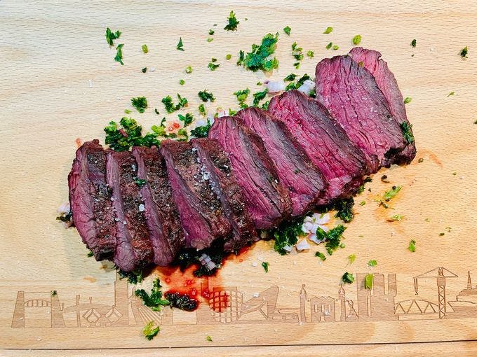 Een aangesneden hanger steak op een houten plank op een board sauce