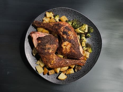 2 kippenbouten van de barbecue op een bord met aardappeltjes en broccoli