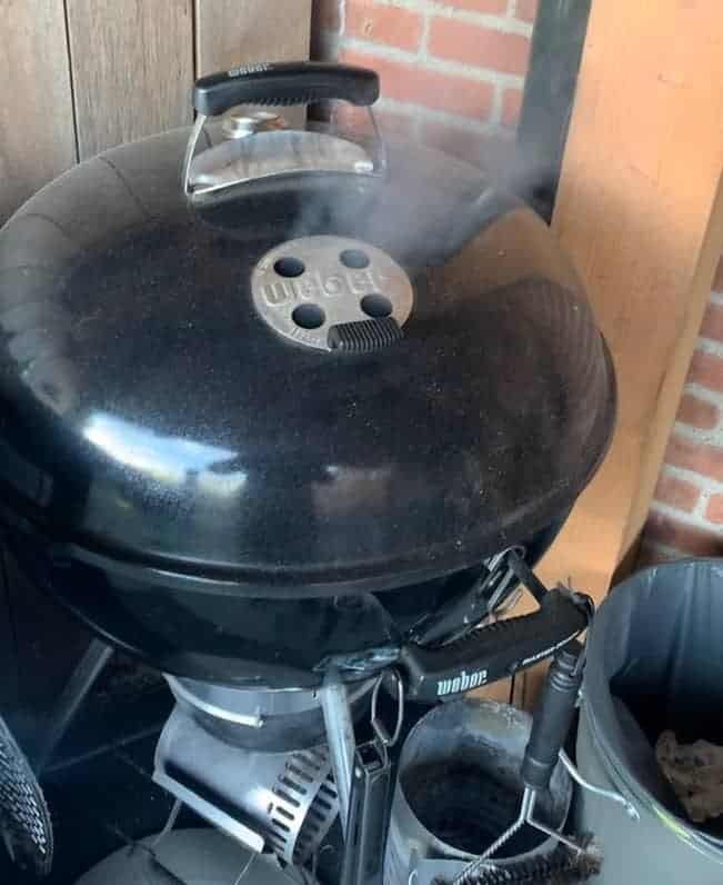 een weber ketel barbecue waar rook uit komt