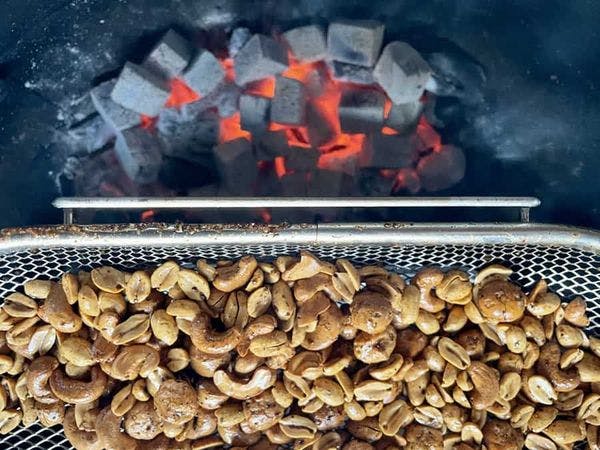 Gerookte noten in een spitmand boven hete briketten